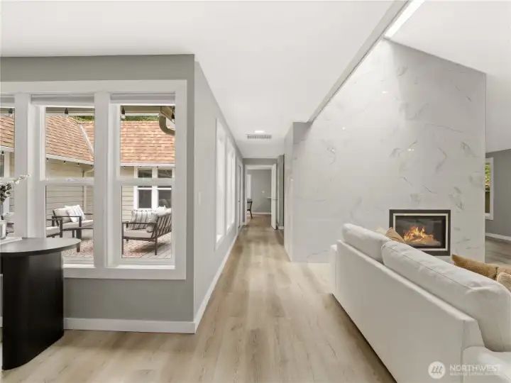 The layout flows effortlessly, with soft tones and clean finishes that feel both elevated and comfortable. HEre you see the 2-story living/dining room on your right, the entry on your left, the hallway that connects the space to the kitchen and the center-of-the-home atrium next to the hall. Truly a unique home!