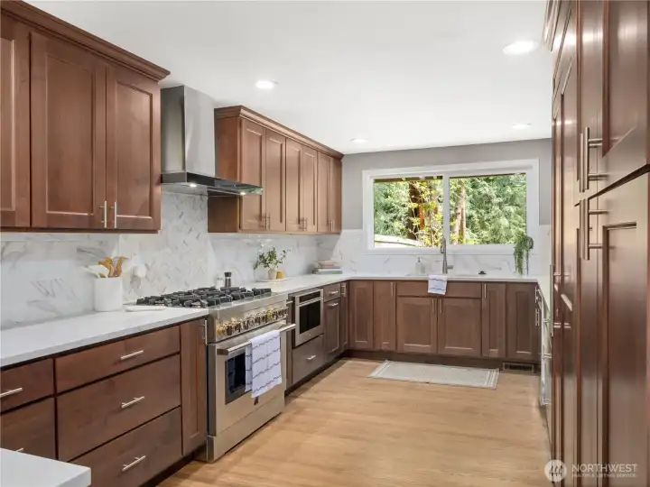 Could this kitchen be more beautiful? Warm wood cabinetry, quartz counters and backsplash, with high-end stainless steel appliances, offering generous workspace and storage.