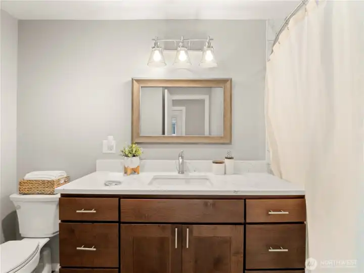 No space untouched, this updated hall bath features a quartz countertop, tons of storage, and modern fixtures with a tub/shower combo.