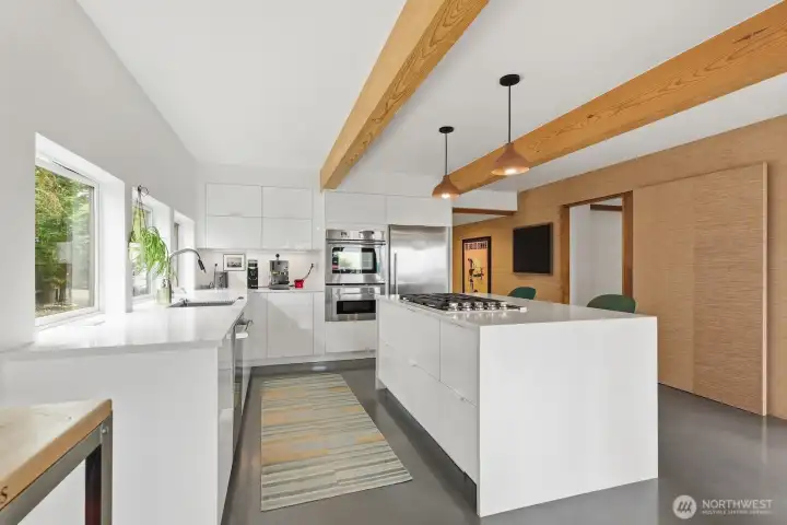Stainless steel appliances, a gas cooktop, sleek modern cabinetry, and a waterfall quartz island - just wow.