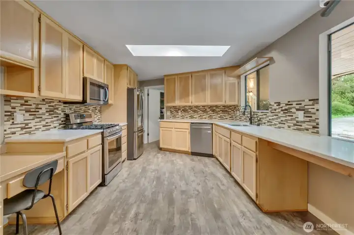 Light and bright kitchen with skylight features vinyl plank flooring, stainless appliances and custom cabinets. Light and bright kitchen with skylight features vinyl plank flooring, stainless appliances and custom cabinets.