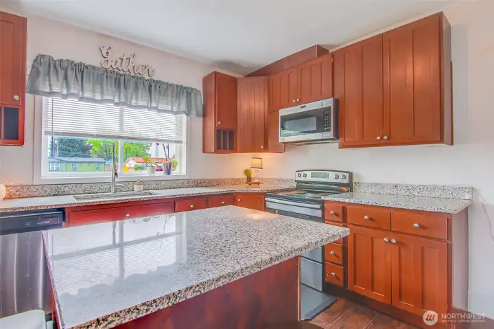 Kitchen with granite slab counters and big picture window.