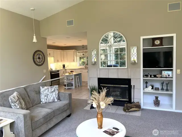 On the opposite side of the windows is a wood fireplace and the rest of the living room and entrance into the kitchen.