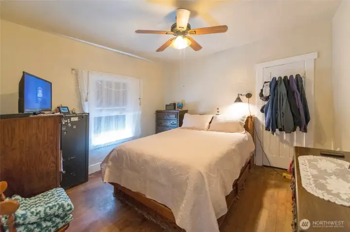 Hardwood floors extend into spacious bedroom, enhancing the home’s classic charm.