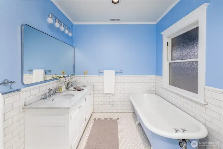 The spa-like full bath features a marble vanity, claw-foot tub and glass shower.