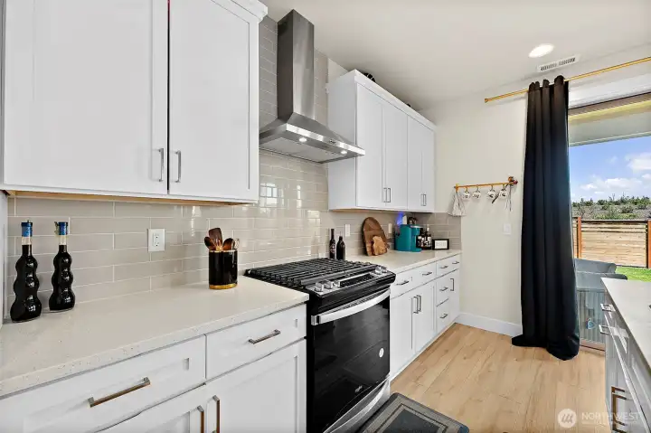 Lots of solid quartz counter space accented with full height subway tile back splash. Make cookies here!