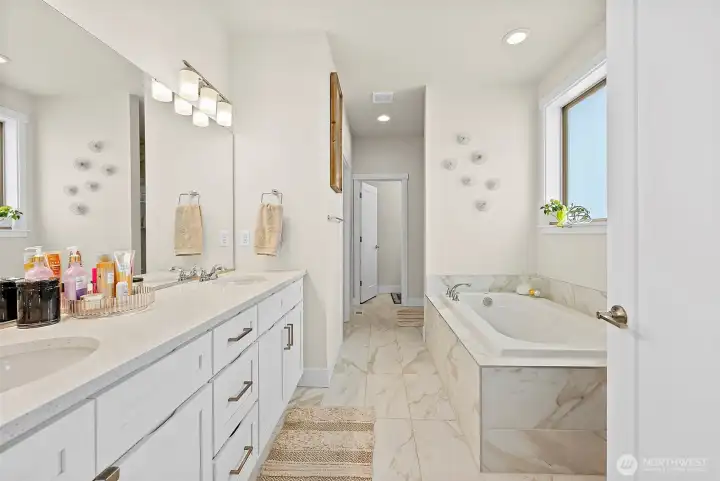 Tile primary bathroom with double sink vanity, private water closet, soaking tub and separate shower.