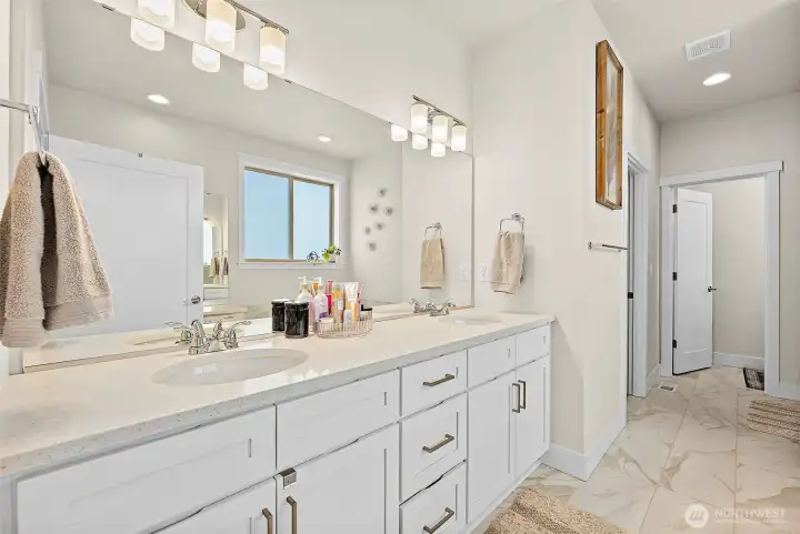Another view, double sink vanity with walk-in closet and private toilet area are the doors beyond.