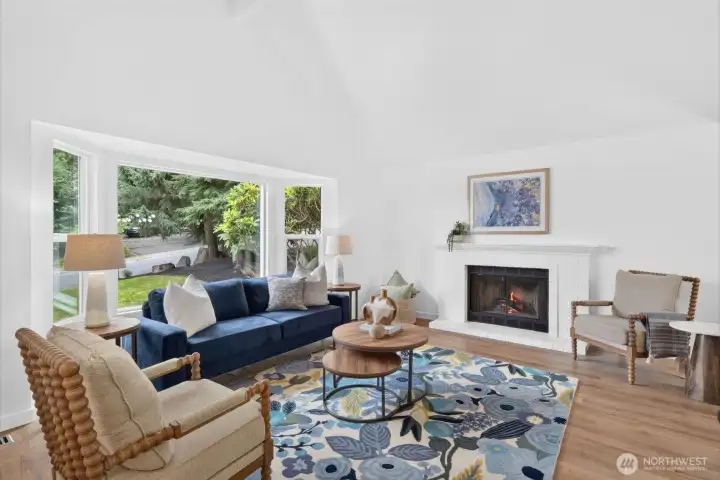 Soaring cathedral ceilings, expansive east-facing windows, and a wood-burning fireplace make this living room bright, welcoming, and ready for cozy mornings and fireside evenings.