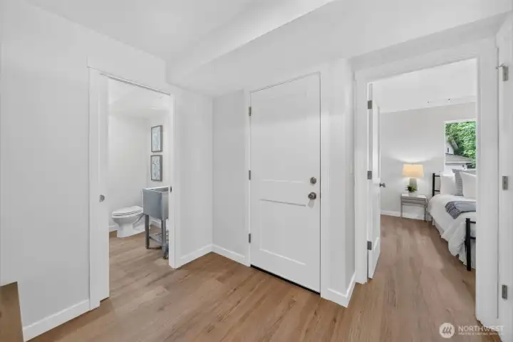 This hardworking lower-level hub keeps everything connected: to the left, the half bath and laundry; straight ahead, garage access; and to the right, the flexible third bedroom. Behind the closed door are the new gas furnace with heat pump and 50-gallon gas water heater.