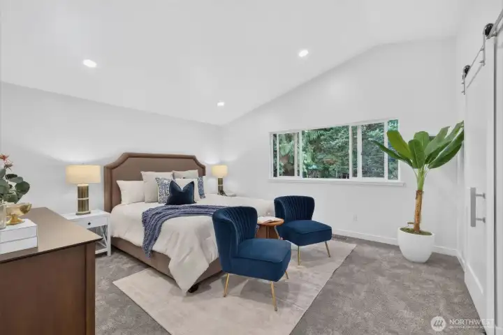 The spacious primary bedroom offers room for a king-size bed, soaring cathedral ceilings, recessed lighting, and a calm, airy feel that makes it a true retreat.
