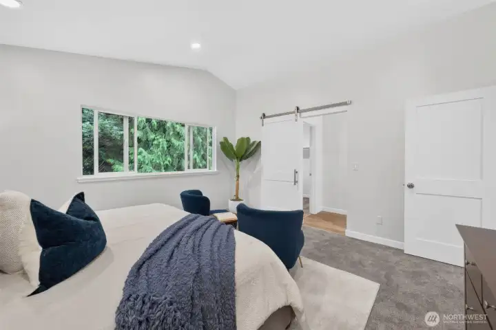 Slide open the modern barn door to reveal the primary ensuite, complete with a walk-in closet and a beautifully renovated three-quarter bath.