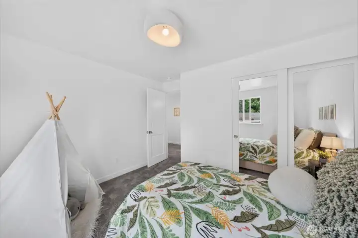 A modern ceiling light and framed mirrored closet doors add style, brightness, and function to this cheerful bedroom.
