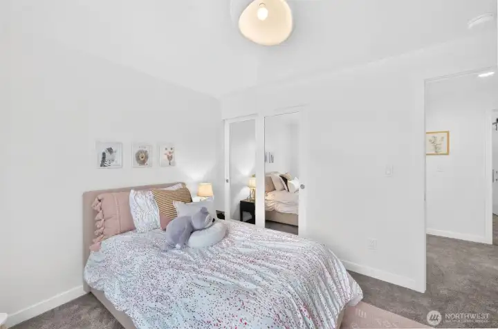 Bedroom two is bright, inviting, and full of possibility, with a modern ceiling light and mirrored closet doors that add both style and function.