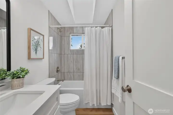 A beautifully renovated main bathroom with a tiled tub surround, modern finishes, and a bright, fresh feel—clean, comfortable, and ready for busy mornings or a long soak at the end of the day.