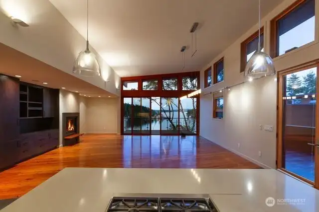 View from open kitchen concept overlooking living room with propane fireplace, built-in bookcase and shelving. Cherry flooring throughout.