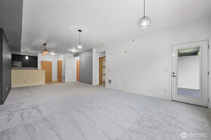View from living room towards dining room/kitchen. Door to balcony on the right, next hallway leads to large closet and main/primary #2 bathroom.