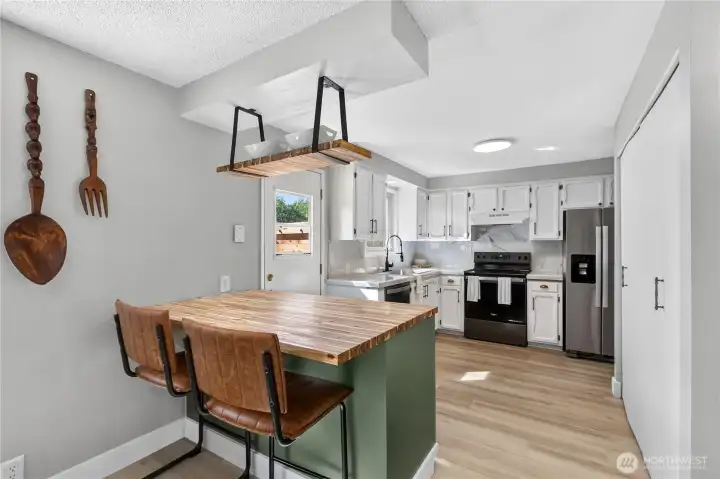 Large butcher block island provides additional prep space, casual seating, and serves as a natural gathering spot adjacent to the dining area. Large butcher block island provides additional prep space, casual seating, and serves as a natural gathering spot adjacent to the dining area.