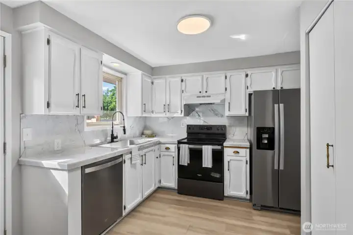 Bright and functional kitchen featuring abundant cabinet storage, updated countertops, stainless steel appliances, and a large window overlooking the backyard. Bright and functional kitchen featuring abundant cabinet storage, updated countertops, stainless steel appliances, and a large window overlooking the backyard.