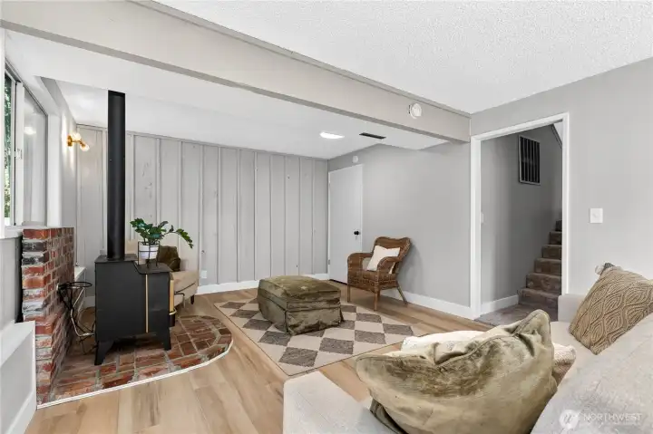 Warm and inviting family room/ flex space centered around a freestanding gas stove on a classic brick hearth, with large windows that bring in natural light and views of the surrounding greenery. Warm and inviting family room/ flex space centered around a freestanding gas stove on a classic brick hearth, with large windows that bring in natural light and views of the surrounding greenery.
