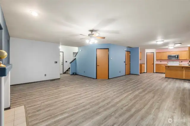 A large greatroom makes a terrific living space. The front door is in the center of this photo, with the downstairs bathroom just to the left of the door, and the stairs to upstairs on the right. The door in the middle photo is a large under stair closet. The door to the right exits to the garage. The door in the kitchen is a large pantry.