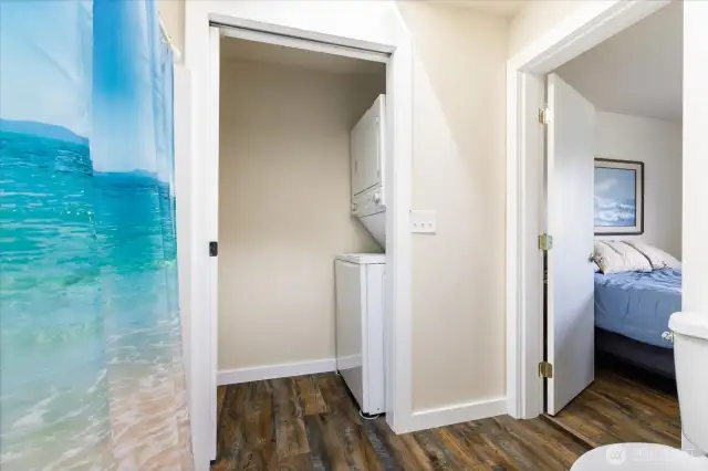 Stacking washer and dryer in side room off bathroom.