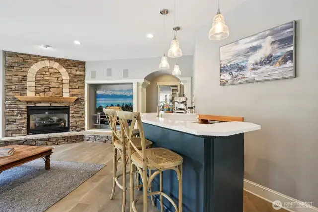 Gather, sip, and unwind in this inviting heart of the home. The custom quartz-topped bar with designer pendant lighting flows seamlessly into the cozy great room, where a gas fireplace framed by arched stonework creates a focal point of warmth and rustic elegance. Perfect for morning espresso or evening wine, this space blends modern comfort with timeless character
