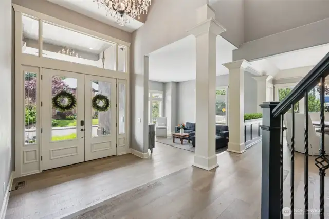 Graceful design begins at the threshold—welcomed by a dramatic RH chandelier, grand double doors, and soaring ceilings. Flooded with natural light, the entry showcases wide-plank engineered oak floors and exquisite five-piece custom base molding for a refined architectural finish. The adjacent formal living and dining areas are framed by elegant columns, offering timeless flow and effortless sophistication throughout