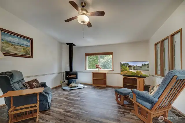 The family room enjoys a cozy wood burning fireplace, ceiling fan, luxury vinyl flooring and a large window to bring in natural light.