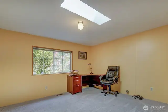 This split floor plan features two more bedrooms at the opposite end of the home. This one has been a favorite office space with skylight and large window showing off the beautiful flowering landscaping.