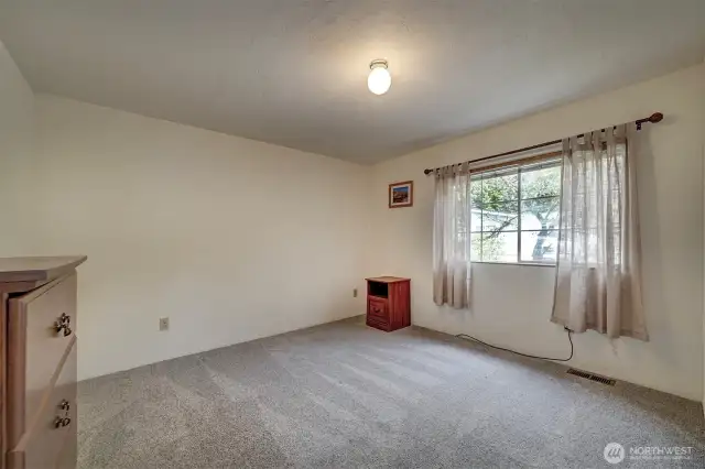 The second guest bedroom with wall to wall carpet and bright window.