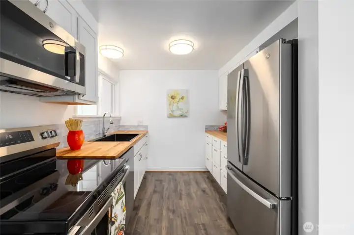 The kitchen with new appliances, cabinets, sink and butcher block counters.