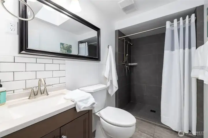 The bathroom has a walk in tiled shower.