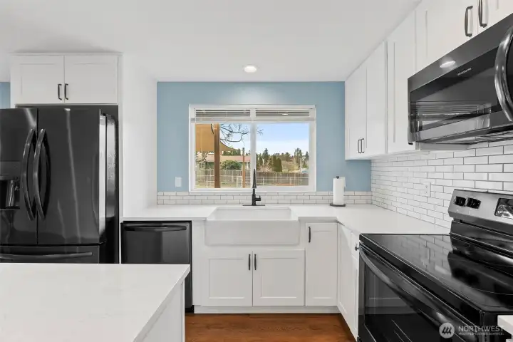 Farmhouse sink, quartz counters, sleek black appliances