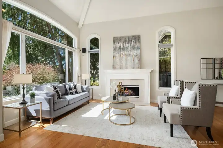 This alternate view of the living room further showcases the space's refined elegance, with large windows flooding the room with natural light, a beautifully appointed fireplace as the focal point, and sophisticated finishes throughout. The generous proportions and timeless design of this inviting space make it the perfect setting for both intimate gatherings and grand entertaining.