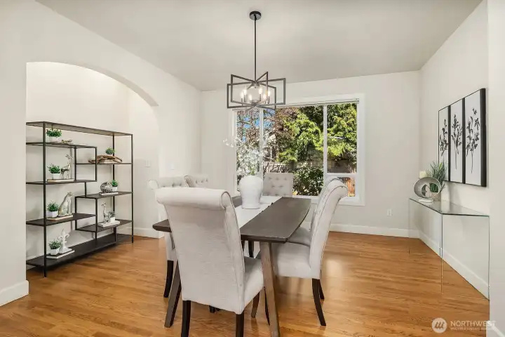 The formal dining room is a elegant and inviting space, featuring rich hardwood floors, an updated chandelier, and a charming arched doorway that adds a distinctive architectural touch. Bathed in natural light from a large window, this generously sized room provides the perfect backdrop for memorable dinner parties and holiday gatherings alike.