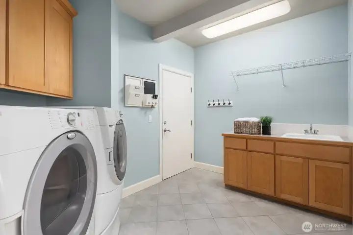 The conveniently located main level laundry room offers ample functionality with a full-size washer and dryer, generous cabinetry for storage, and a utility sink — making laundry day as efficient and organized as possible. This well-designed space adds a practical and highly sought-after amenity that enhances the everyday livability of this exceptional home.