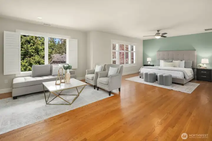 The expansive primary suite is truly in a class of its own, featuring a generous sitting area with gleaming hardwood floors, large windows overlooking the lush surroundings, and a warm dual-sided fireplace that connects seamlessly to the bedroom beyond. This exceptional space offers a rare level of luxury and comfort, creating a private sanctuary where every detail has been thoughtfully considered.