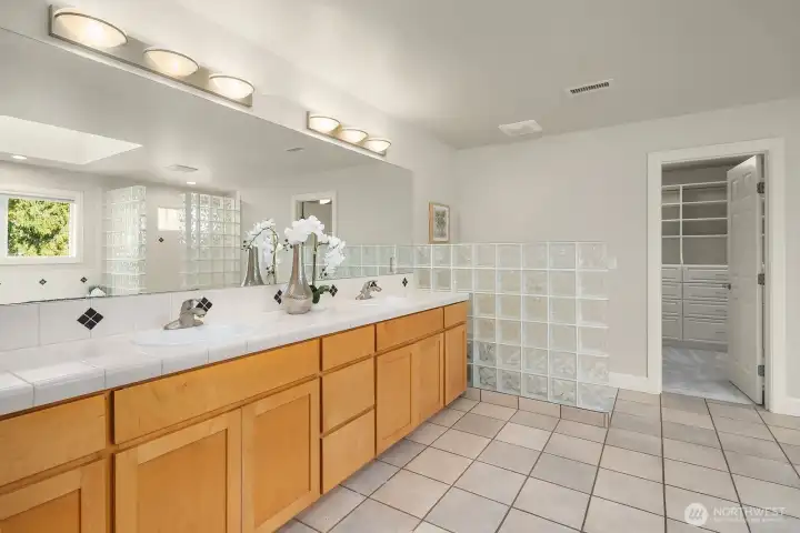 This luxurious five-piece primary bath is a true spa-like retreat, featuring dual vanities with abundant counter space, skylights that bathe the room in natural light, and a separate soaking tub and shower. The generous proportions, quality finishes, and thoughtful layout of this exceptional bath make it a standout feature of the already impressive primary suite.