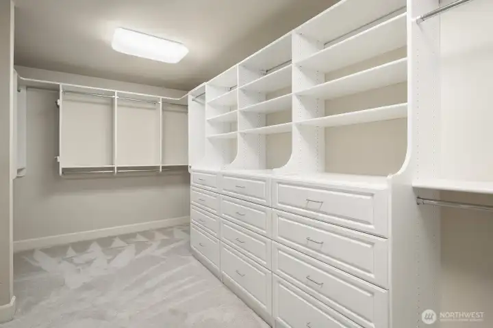 This impressively sized primary suite walk-in closet features an abundance of California Closets built-in shelving, hanging space, and organizational systems designed to accommodate even the most extensive wardrobe with ease. The generous proportions and thoughtfully designed storage solutions make this exceptional closet a true luxury amenity that perfectly completes the primary suite experience.