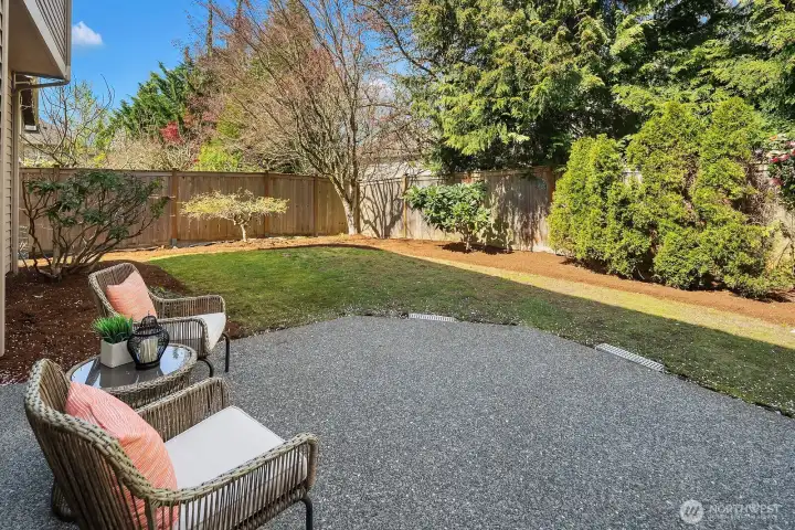This inviting backyard patio provides a wonderful outdoor living space, featuring a generous gravel seating area perfectly suited for outdoor furniture, al fresco dining, or relaxed entertaining within the privacy of the fully fenced yard. Surrounded by lush, mature landscaping and bathed in natural light, this charming patio is the ideal spot to unwind and enjoy the best of Pacific Northwest outdoor living.