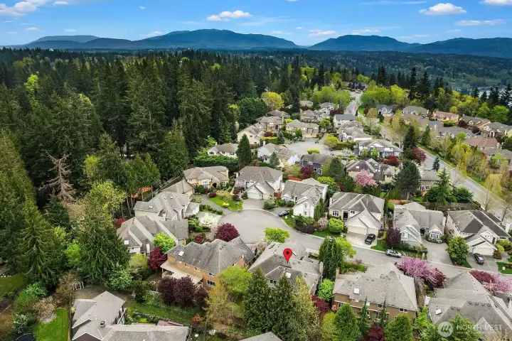 This breathtaking aerial view captures the home's enviable setting within the beautifully established Sterling Woods community of Timberline, surrounded by lush Pacific Northwest forest and the stunning backdrop of the Cascade foothills. The serene, tree-canopied neighborhood perfectly conveys the exceptional quality of life, privacy, and natural beauty that make this community one of the most sought-after addresses in the area.