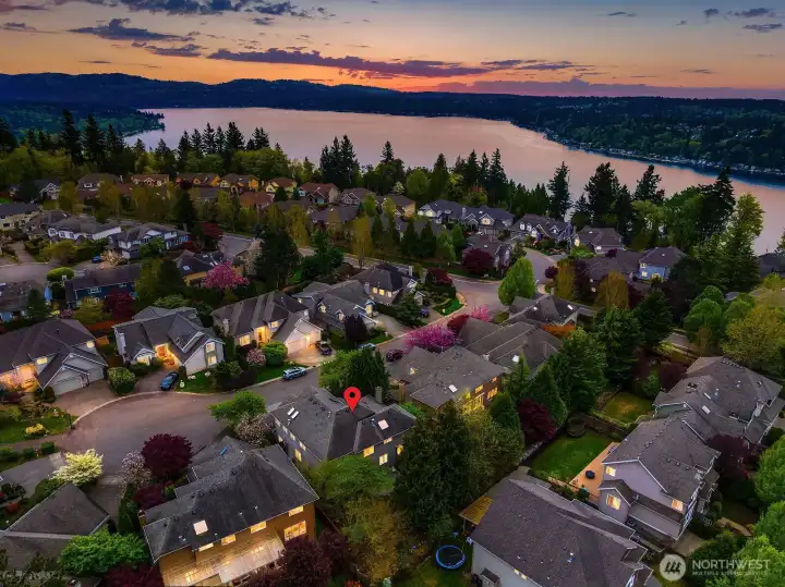 This absolutely stunning twilight aerial shot captures the neighborhood bathed in warm evening light with the shimmering waters of Lake Sammamish glowing beneath a spectacular sunset sky — a truly awe-inspiring image that speaks to the unparalleled beauty and lifestyle of this exceptional Timberline location. This magnificent final photo perfectly encapsulates everything that makes this home and community so extraordinarily special.