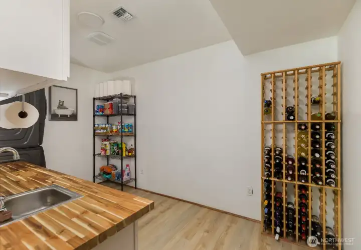 Laundry room has cabinets, matching counter tops, working sink, shelving & wine rack that conveys to new owners with the sale of the house.