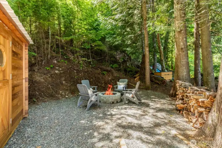 2nd Fire pit, additonal firewood located next to redwood sauna.  Kayaks and Flat Bottom motorboat with batteries in the background will convey with the sauna and adirondack to new owners.