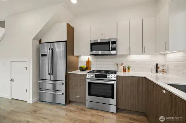 Chefs kitchen with quartz countertops, gas cooking, stainless appliances and tons of storage cabinets.