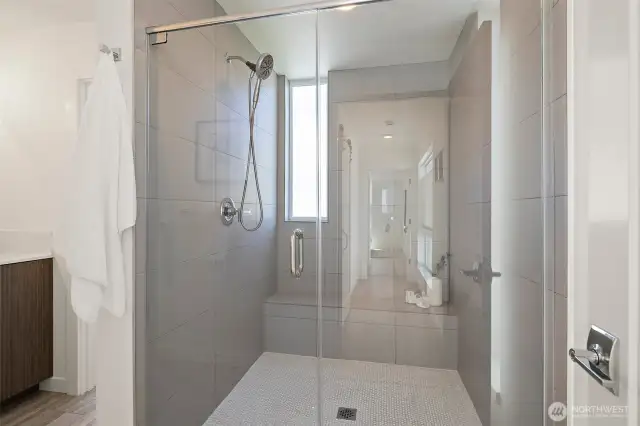 Primary suite bathroom with frameless shower door, tile bench and timeless style.