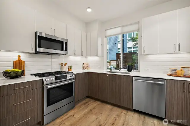 Chefs kitchen with quartz countertops, gas cooking, stainless appliances and tons of storage cabinets.