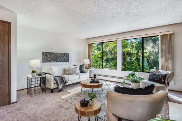 The living room has a serene outlook with lots of trees.