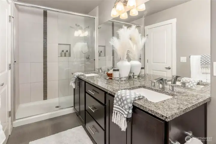 Ensuite primary bedroom's three-quarter bath with dual vanity and designer shower.